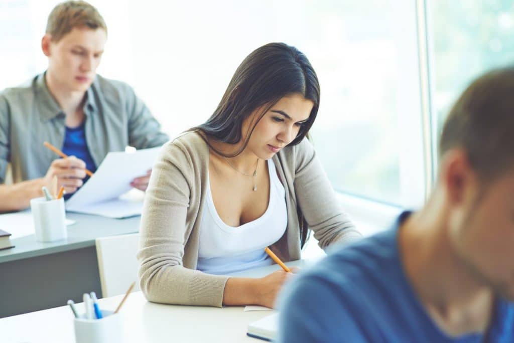 Tres personas realizando un examen teórico de las oposiciones de Educación Física.